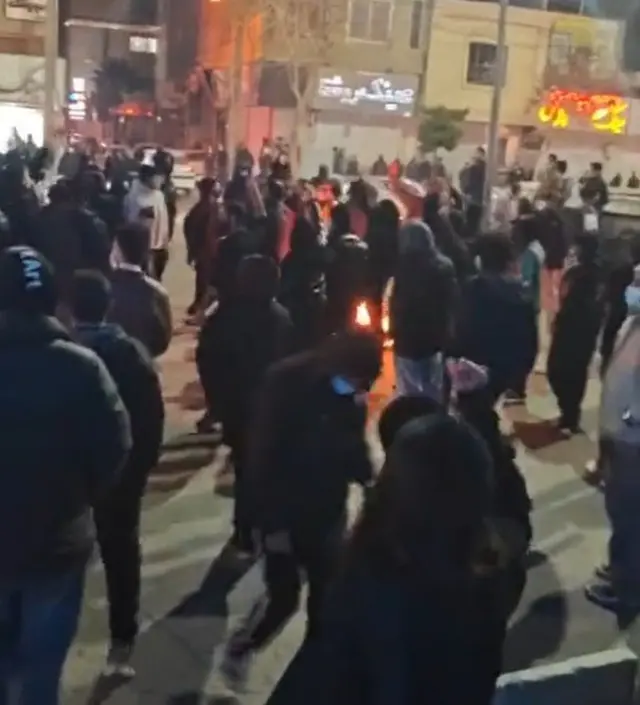 রাতের বেলা একটি রাস্তায় বিক্ষোভকারীরা আগুন জ্বালিয়ে বিক্ষোভ করছে 