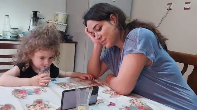 عکسی از نازنین و دلسا در کنار هم که پشت میز نشسته‌اند و دلسا در حال تماشا کردن موبایل است