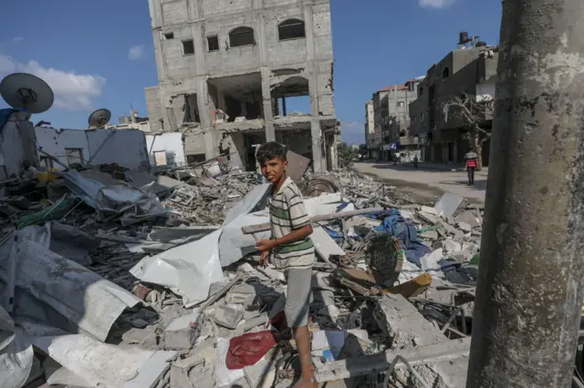 Menino em frente a destroços de casa de família destruída após ataque aéreo em Gaza