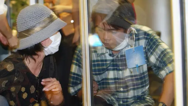 A man sits behind a glass wall in quarantine in Hanoi during the Sars epidemic in 2003