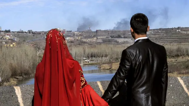 3 Şubat 2016'da çekilen bu fotoğrafta, düğün kıyafetleriyle poz veren bu çift, Diyarbakır'ın Sur ilçesinden çatışmalar nedeniyle yükselen dumana bakıyor