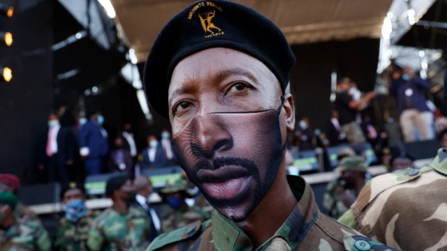 A member of the uMkhonto we Sizwe Military Veterans Association (MKMVA), in a face mask, stands next to a stage moments before former South African President Jacob Zuma addresses his supporters in Pietermaritzburg, South Africa - Wednesday 26 May 2021