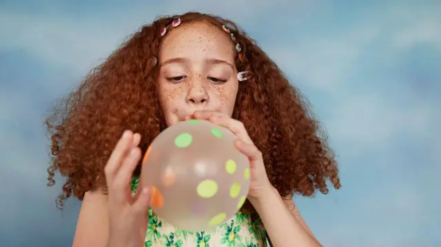 Existe um centro no Universo? Por que essa questão científica desafia os limites da nossa imaginação 2 Menina sopra um balão com pontos na sua superfície