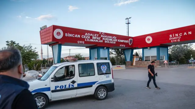 Sincan Cezaevi kapısı önünde bir polis arabası. Bir polis ve bir adam kapıya bakıyor