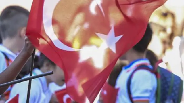 Ankara'da, 2023-2024 eğitim-öğretim yılında çekilmiş bir fotoğraf. Ellerinde Türk bayraklı bir grup ilkokul öğrencisi görülüyor. Birinin arkasında sırt çantası var. 