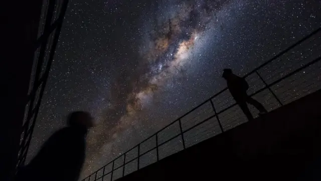 شخصان يراقبان نجوماً في جو صافٍ ومظلم