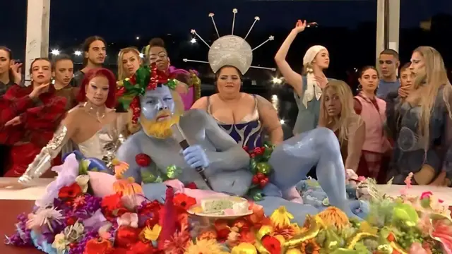 프랑스 파리올림픽 개회식 장면. 커다란 테이블 위에 하늘색으로 몸 전체를 칠한 나체 인물과 주변에는 드래그 퀸들, 과일 그릇에 앉아 노래를 부르는 가수가 있다.