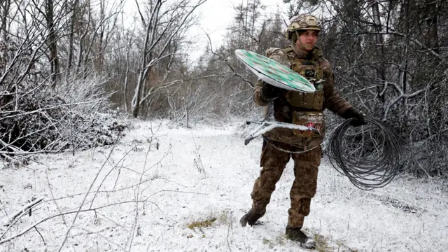 A Ukrainian serviceman walks with a disconnected Starlink terminal