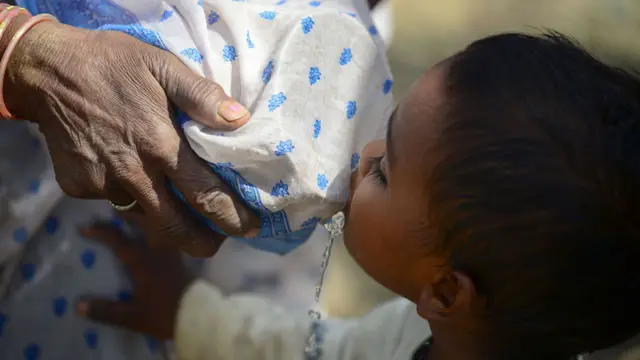 Niño tomando agua de un recipiente en el que un adulto colocó una tela para filtrar el líquido