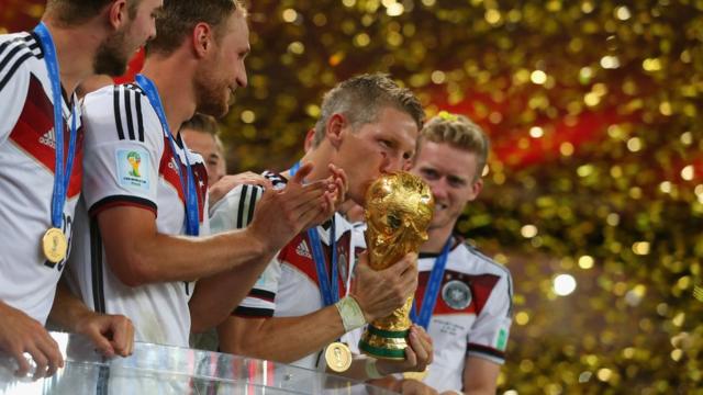 Bastian Schweinsteiger of Germany kisses the World Cup trophy to celebrate with his teammates during the award ceremony after the 2014 FIFA World Cup Brazil Final