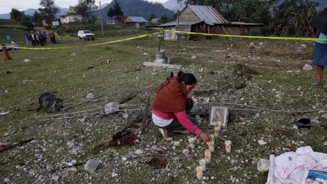 Una mujer poniéndole velas a la Virgen de Guadalupe