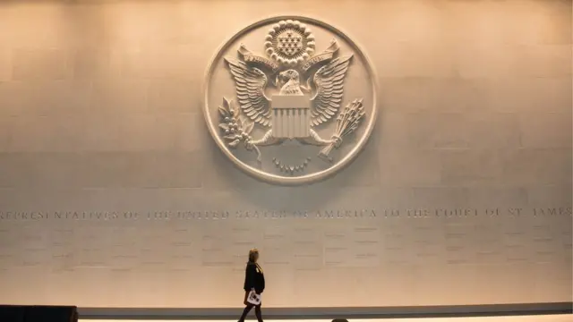Mujer caminando en la embajada de Estados Unidos en Londres, Reino Unido.