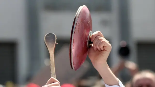 Cucharón de madera golpeando la tapa de una olla.