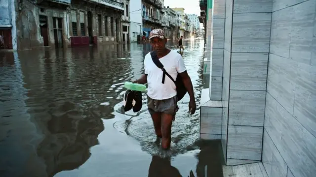 Homem caminhando por rua inundadabonuskodebet365Cuba