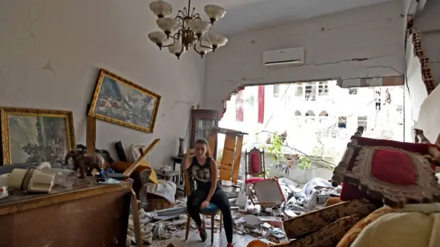 Une femme est assise au milieu des décombres de sa maison endommagée dans la capitale libanaise, Beyrouth, le 6 août 2020, deux jours après qu'une explosion massive ait secoué la capitale libanaise.