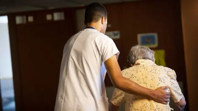 عامل تمريض يساعد سيدة مسنة