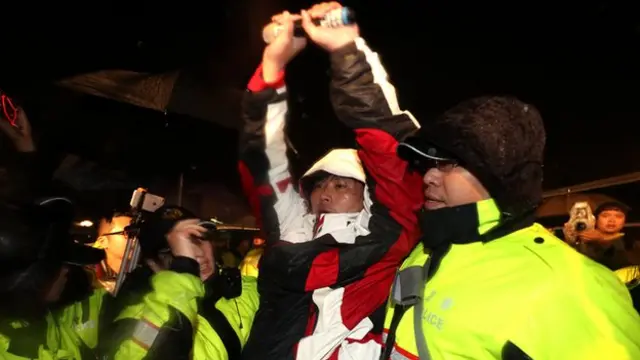 黄国昌在警方戒护下离开总统府前,高举双手。