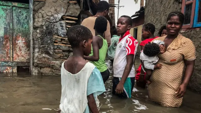 familia ikiwa imesimama nje ya nyumba yao iliokumba na mafuriko