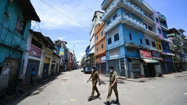 ஏப்ரல் 28, 2022 அன்று கொழும்பில் மூடப்பட்டிருக்கும் ஐந்தாவது குறுக்குத் தெரு மொத்த விற்பனைச் சந்தையில் ஒரு தெருவில் போலீஸ்காரர் நடந்து செல்கிறார்