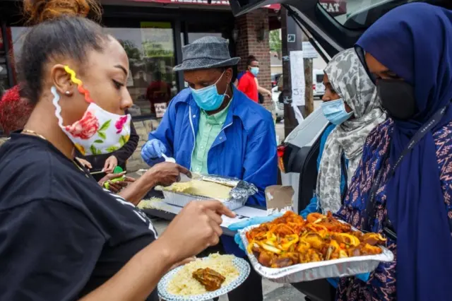 La communauté somalienne américaine sert un déjeuner fait maison près d'un mémorial improvisé à George Floyd près de l'endroit où il est mort pendant sa détention par la police de Minneapolis, le 27 mai 2020 à Minneapolis, Minnesota.