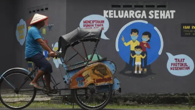 Warga melintas di depan mural edukasi kesehatan di kawasan Bibis, Banjarsari, Solo, Jawa Tengah, Selasa (06/04)