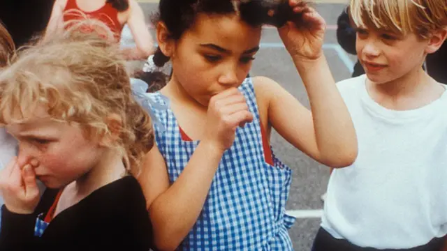 3 niños pequeños y la de en medio chupándose el dedo.