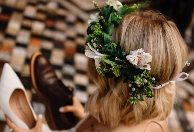 Venac od cveća na glavi mlade koja gleda u žensku i mušku cipelu