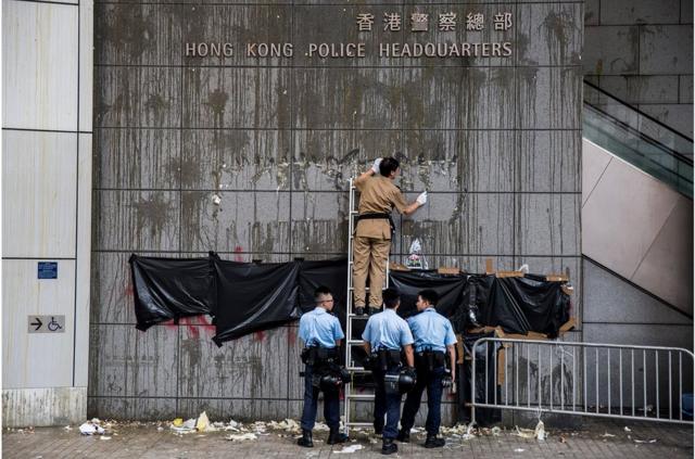 香港警察总部被大批示威者包围，外墙墙面被示威者投掷鸡蛋，警方派人清理。
