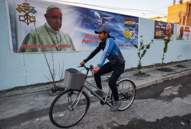 ملصقات احتفالية بزيارة البابا في أحد شوارع بغداد