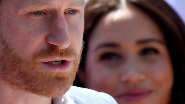 Prince Harry, Duke of Sussex, gives a speech as his wife Meghan, Duchess of Sussex, looks on near Johannesburg, South Africa