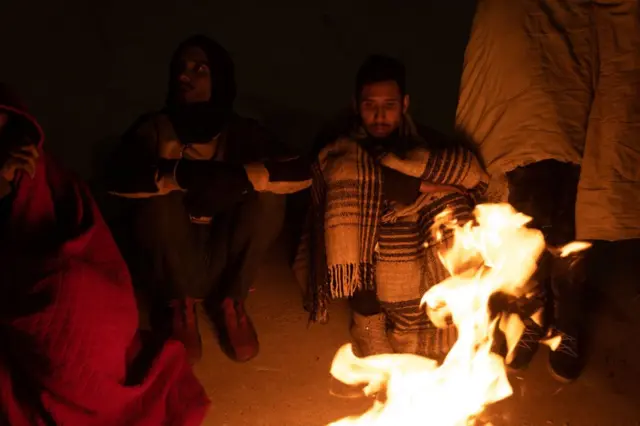 Migrantes en Ciudad Juárez se calientan junto a una hoguera mientras esperan la oportunidad de cruzar el río Bravo hacia El Paso, Texas, EE.UU., el 20 de diciembre de 2022.