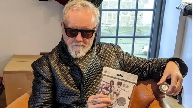 Роджер Тейлор держит в руках памятную монету