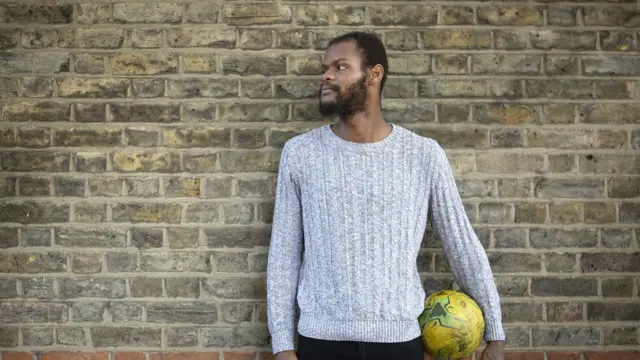 Patrick George appuyé contre un mur avec un ballon de football