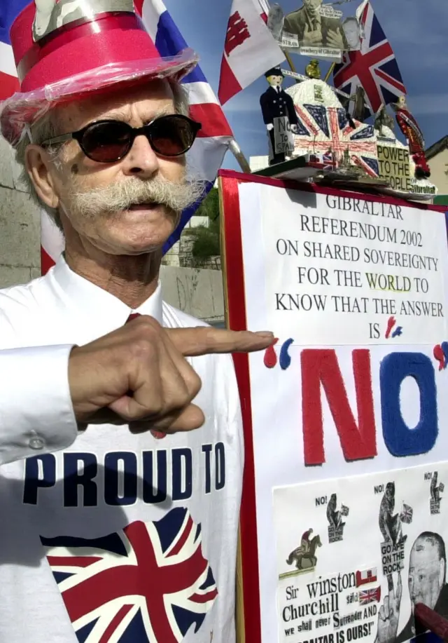 Un manifestante con una camisa que dice "Orgulloso de" y una bandera británica