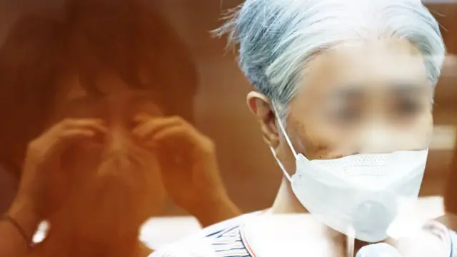 한 어르신이 유리벽을 사이에 두고 가족들과 비대면 면회를 하고 있다. 눈가를 훔치는 한 가족의 모습이 유리벽에 비치고 있다.