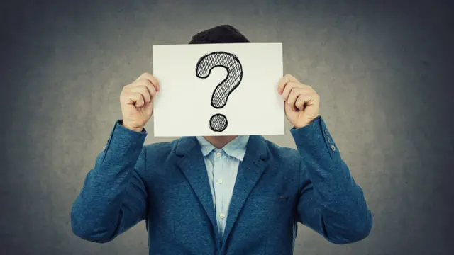 Joven con el rostro tapado con un cartel con el signo de interrogación