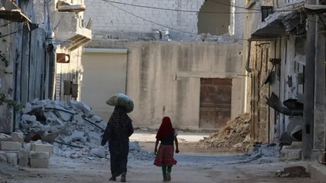 Una mujer y una niña caminan por las calles destruidas de Alepo.