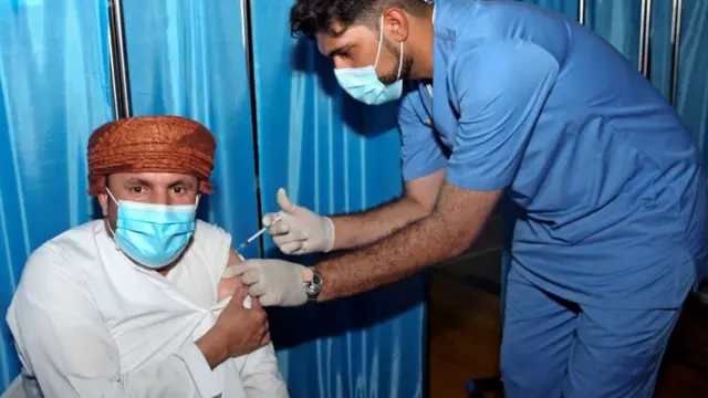 رجل عماني يتلقى جرعة من لقاح فايزر في مجمع السلطان قابوس الرياضي بالعاصمة العمانية