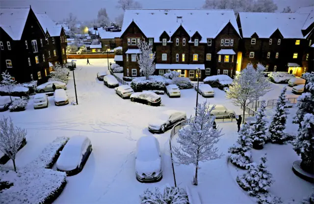 People walk along a snow covered road in Altrincham