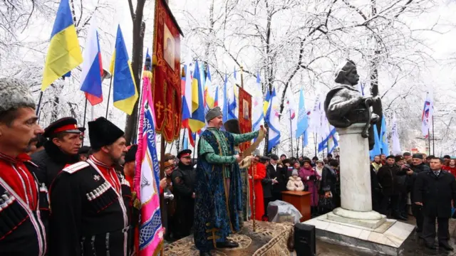 Учасники урочистого збору з нагоди річниці Переяславської ради тримають українські та російські прапори поряд із пам'ятником Богдану Хмельницькому в Сімферополі