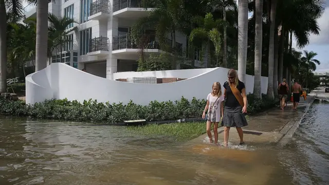 Unas personas caminan por una calle inundada de Fort Lauderdale.