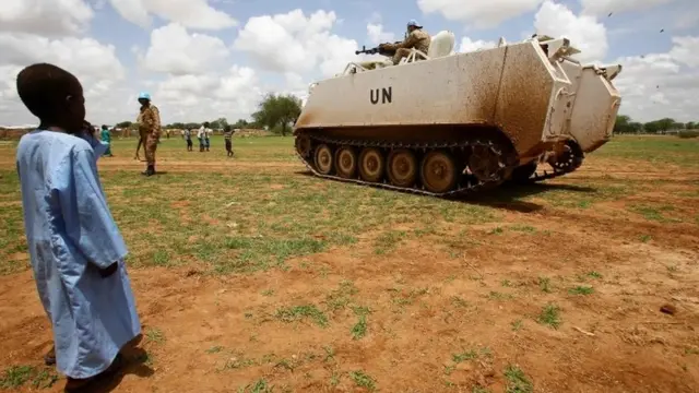 Ilmo yar ayaa eegaya gaadiid kuwa dagaalka oo ay leedahay Qaramada Midoobay, gobolka Dafur ee dalka Sudan