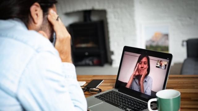 Un hombre conversa con una mujer a través de una videollamada por computador.