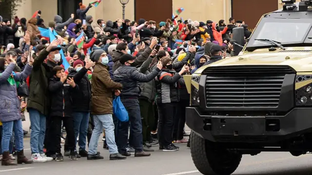 İnsanlar hərbi maşın fonunda