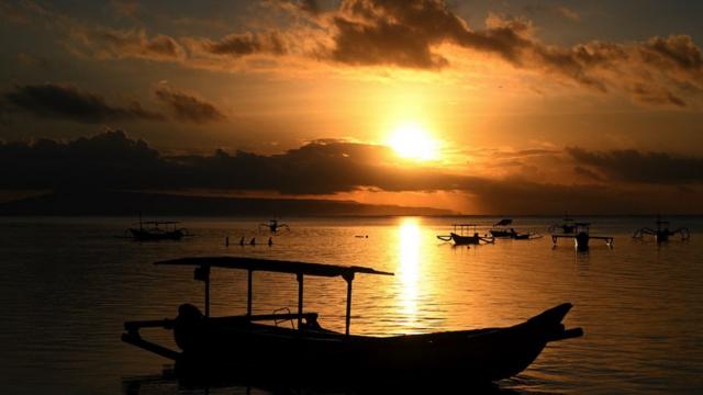 People watch the sunrise at Sanur beach on the Indonesian resort island of Bali on 6 February, 2024