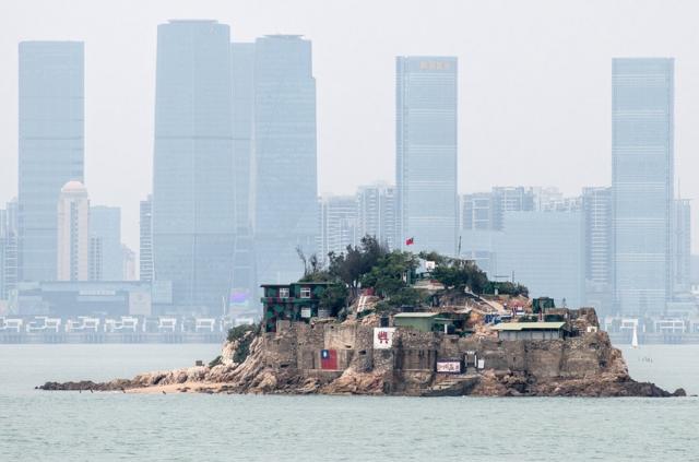 台湾金门离岛小岛——狮屿。岛上插有中华民国青天白日旗，对面高楼大厦是福建厦门市（2018年4月20日资料照片）。