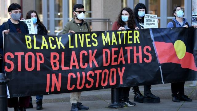 澳大利亚新南威尔士州最高法院外一群“黑人的命也是命”示威者举起呼吁停止黑人在押期间死亡问题标语（23/7/2020）
