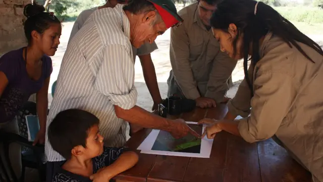 Micaela Camino mostrando un mapa de tierras a un integrante de una comunidad en el Chaco argentino