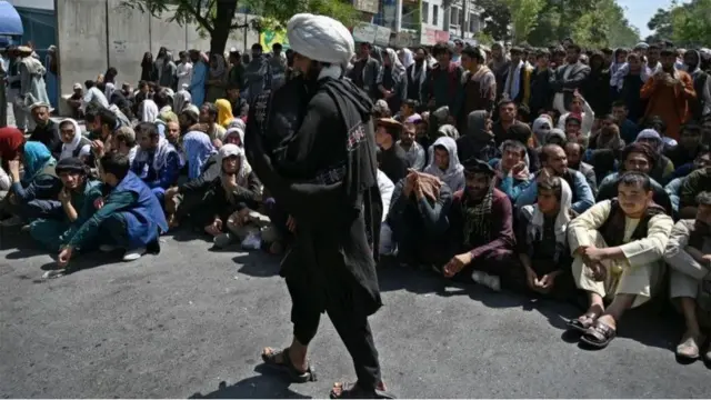 কাবুলে একটি ব্যাংকের সামনে টাকা তোলার ভীড় পাহারা দিচ্ছে এক তালেবান যোদ্ধা