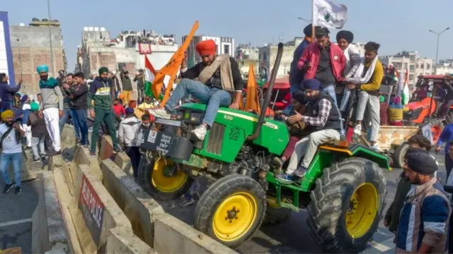 Agricultores dirigem um trator sobre uma barricada na fronteira Déli-Ghazipur